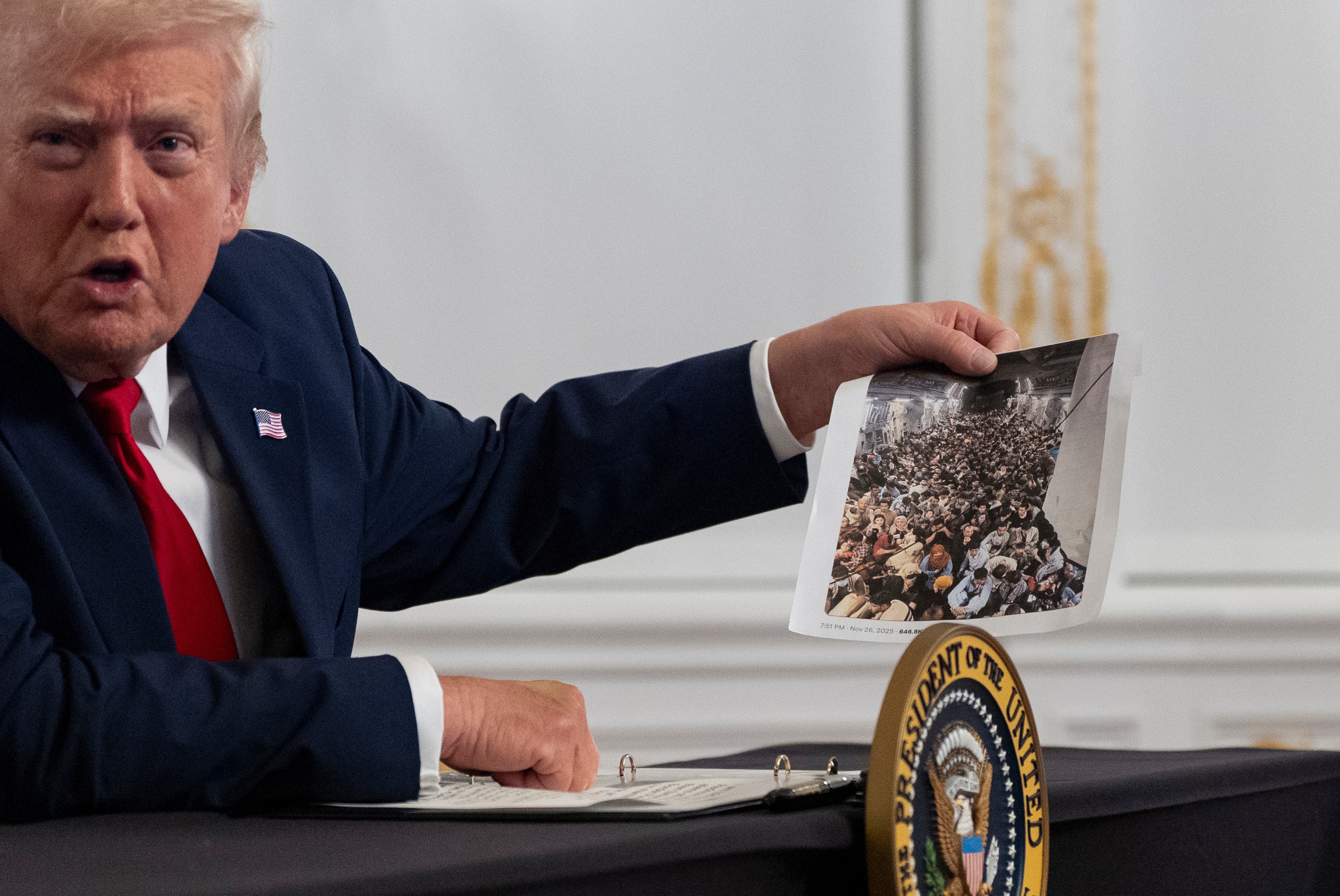 President Donald Trump holds up a photograph as he speaks to reporters after speaking to troops via video from his Mar-a-Lago estate on Thanksgiving, Thursday, Nov. 27, 2025, in Palm Beach, Fla.